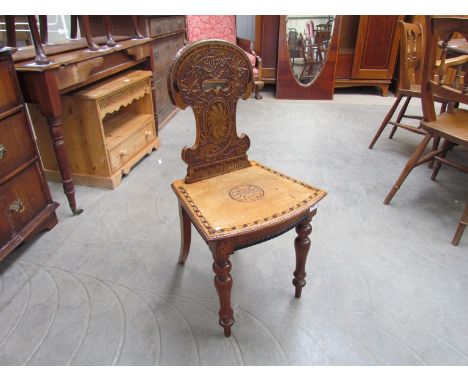 Circa 1880 an inlaid fruitwood hall chair, the shaped back with fret handle and carved grape and vine decoration over a bow f