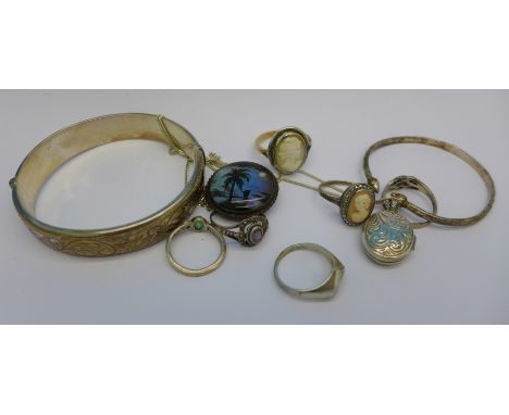 A silver bangle, a silver locket, a silver brooch lacking pin, one other bangle and six rings including silver