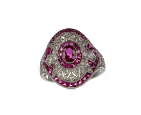 RUBY, SPINEL AND DIAMOND RING, set with a central oval ruby bordered by round brilliant cut diamonds and calibre cut rubies a