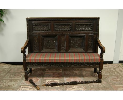 A Victorian and earlier oak hall settle, 152cm wide and 122cm high, the lower frieze rail having carved decoration and dated 