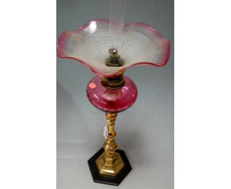 Circa 1900 brass pedestal oil lamp having cranberry tinted folded shade, and cranberry reservoir