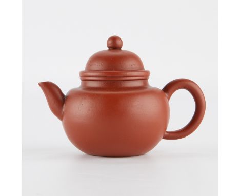 Chinese Yixing zisha teapot with a smooth rounded body and domed lid. Marked with a seal along the bottom indicating it as a 