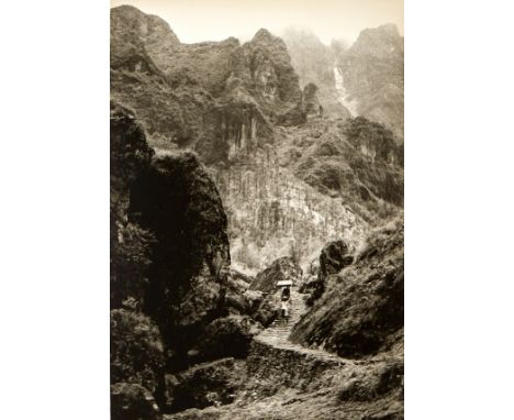 Chin San Long (Lang Jingshan) (Chinese, 1892-1995). Photograph depicting a figure carrying a load up a curving path in the mo