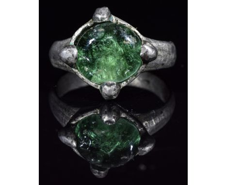 Ca.1000 AD. Interesting wearable Viking silver ring with a clasped bezel holding shiny green gem; representing the eye of the