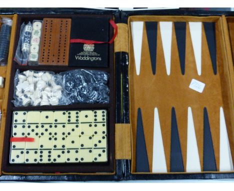 A LEATHER CASED GAMES COMPENDIUM TO INCLUDE DOMINOES, CHESS, BACKGAMMON, DICE AND WADDINGTON'S CARDS.