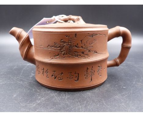 A YIXING TEAPOT WITH BAMBOO SPOUT AND HANDLES, THE TWO SECTION CYLINDRICAL BODY INSCRIBED ABOUT COUNTRY SCENES, BACKSTAMPED C