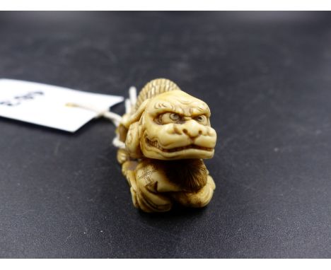 A JAPANESE MARINE IVORY NETSUKE CARVED AS ONE CHILD WEARING A LION MASK RAISING THE MASK HEAD OF A BABY HOLDING A RATTLE, SIG