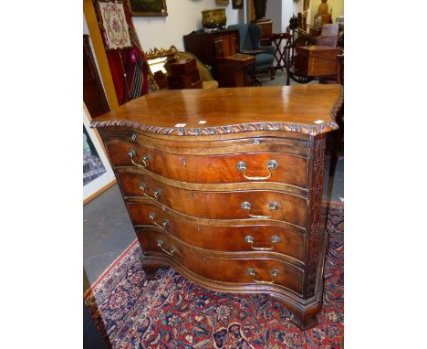 AN ANTIQUE CARVED MAHOGANY SERPENTINE FORM CHEST WITH BRUSHING SLIDE IN THE CHIPPENDALE TASTE, BLIND FRET CANTED CORNERS FLAN