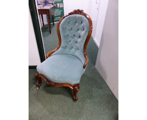 A CARVED WALNUT BUTTON BACK VICTORIAN LADIES CHAIR WITH FLORAL CREST AND APRON ON CABRIOLE LEGS.