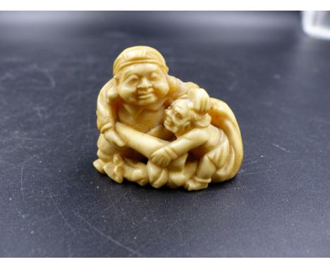 A JAPANESE MARINE IVORY NETSUKE CARVED AS A DAIKOKU TACKLING AN ONI ATTEMPTING  TO RAID HIS SACK OF GOOD FORTUNE.   W.4.5CMS.