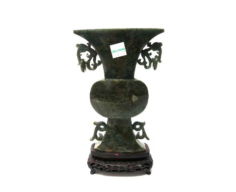 A Chinese spinach jade vase, 20th century, of flattened gu shape with ring handles, 16.5cm. high, wood stand.