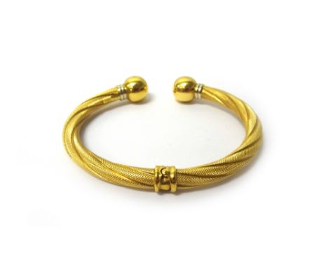 A gold torque bangle, in a decorated twisted design, with plain spherical terminals, detailed 750, gross weight 15.5 gms.