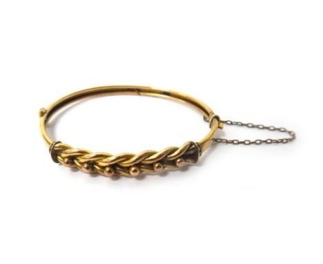 A gold oval hinged bangle, the front in a beaded and interwoven design, on a snap clasp, detailed 9 CT, fitted with a safety 