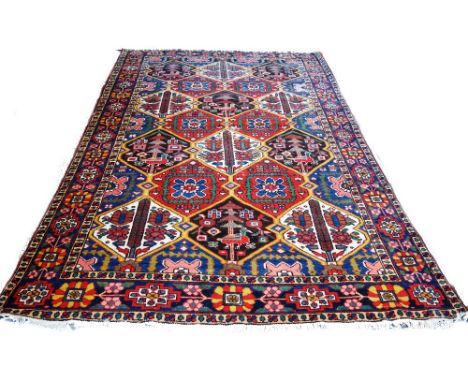 A Bakhtiari carpet, Persian, the trellis field filled with flowers, trees and birds, with an indigo flowerhead border, 318cm 