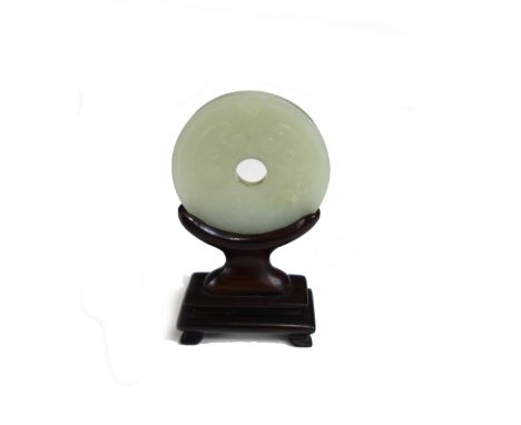 A Chinese pale celadon jade bi disc, late 19th/20th century, carved with ruyi-type panels against a cross hatched ground, 5.3