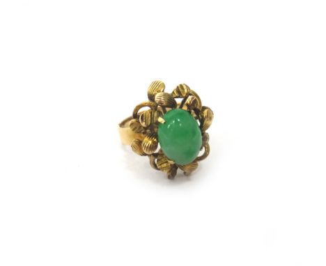 A gold ring, claw set with an oval cabochon jade, within a foliate surround, detailed 18 K, ring size L, gross weight 5.2 gms