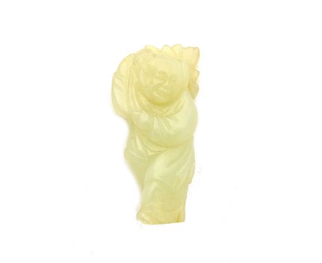A Chinese pale celadon jade figure of a boy, late 19th/20th century, carved stand carrying a leafy branch across his shoulder