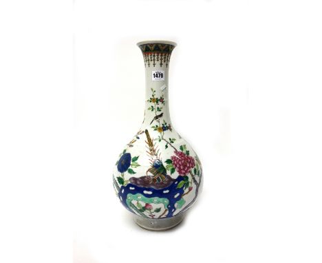 A tall Chinese famille-rose bottle vase, late 19th century, painted with a pheasant perched on rocks amongst flowering shrubs