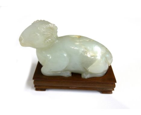 A Chinese pale celadon jade carving of a recumbent ram, 20th century, the stone with brown and cream inclusions, 11cm. length