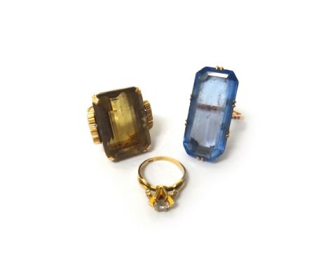 A gold ring, claw set with a large rectangular step cut smoky quartz, between decorated shoulders, detailed 18 K, a gold and 