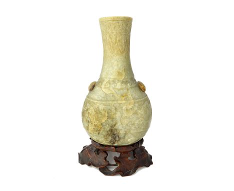 A Chinese grey, russet and black jade vase, Ming dynasty, of flattened bottle form, carved with a band of taotie masks  betwe