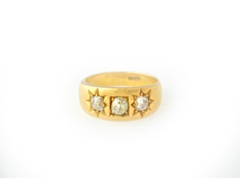 A gold and diamond set three stone ring, square gypsy set with a cushion shaped diamond to the centre, between two star gypsy