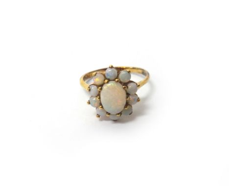 A 9ct gold and opal eleven stone cluster ring, claw set with the oval opal at the centre, in a surround of ten circular opals