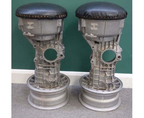 A pair of 20th century bar stools, the padded circular tops on polished steel engine components and alloy wheel bases, 80cm h