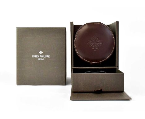 PATEK PHILIPPE; a brown leather covered watch self-winding cylinder, in original brown card outer, both with gold leaf brandi