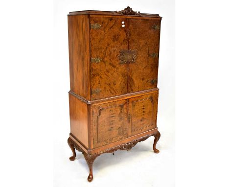 A 1930s walnut drinks cabinet, with ornate brass escutcheons and hinges, with a maple-lined interior with various fittings, m