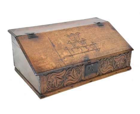An 18th century large oak Bible box, with slope front and wrought iron hinges, carved with the initials 'EW' over '1739', the