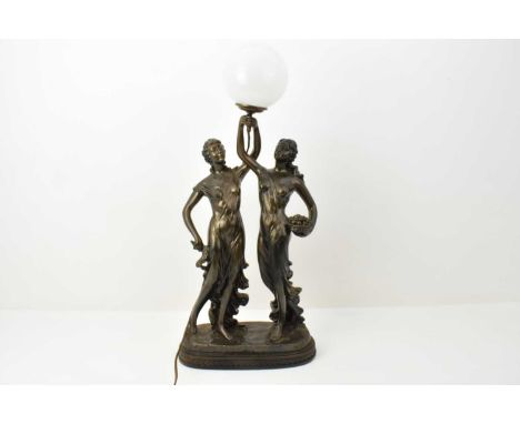 A modern bronzed lamp in the form of two entwined maidens holding a globe to the middle, one with basket of fruit, the other 