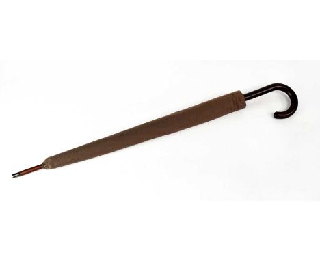 PATEK PHILIPPE; a branded large dark brown umbrella, with slip cover, length approx. 102cm.Footnote: In original plastic wrap
