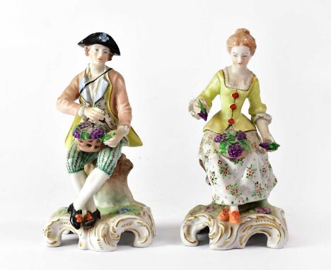 DRESDEN; a pair of late 19th/early 20th century figures of a man and a woman both sitting on tree stumps with a basket of gra