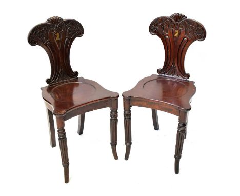 A pair of 19th century hall chairs, the fan-shaped back with floral carved detail and shell top, with central brass inlaid cr