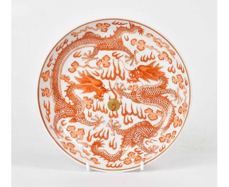 A Chinese Qing dynasty dish, painted in ironstone red, with two dragons chasing a central golden pearl, amongst clouds, with 