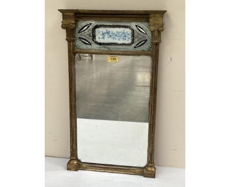 A Regency gilt pier glass, the frame with ionic pilasters enclosing a verre-eglomise panel painted with flowers (cracked) and