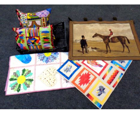 A crate of patchwork throws, wall hanging depicting man on horse, two tapestry cushions 
