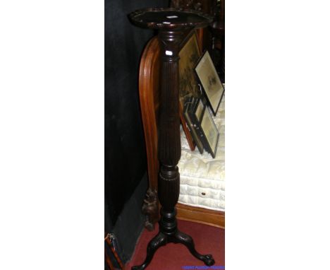 A mahogany torchere on turned and reeded column and tripod support