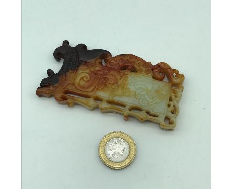 A Finely carved Chinese jade token/ pendant showing dark brown tinges. Measures 9cm in length 