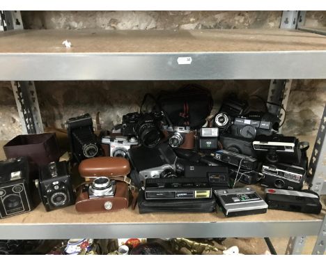 A Shelf of vintage cameras which includes Kodak, Yashica, Cosina CSM, Kodak bellow and box cameras 