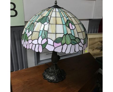 A Large Tiffany style table lamp, Designed with a bronzed metal base. In a working condition. Measures 65cm in height 