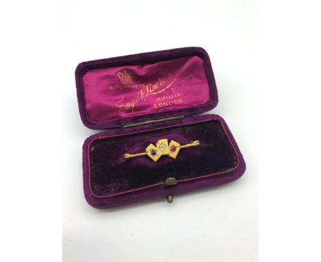 A High grade (22-24ct) gold bar brooch set with three playing cards which hold semi precious stones, Club holds a single sapp