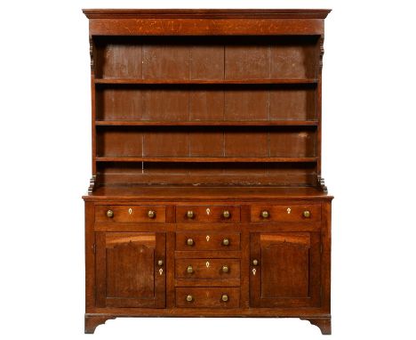AN OAK DRESSER NORTH WALES,&nbsp; EARLY 19TH C with moulded cornice to the boarded rack, profile corbels and matching bases, 