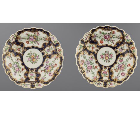 A PAIR OF WORCESTER SCALE BLUE GROUND PLATES, C1770&nbsp;painted with floral reserves in slightly upturned, scalloped gilt ri