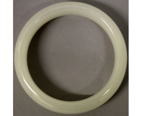 A CHINESE WHITE JADE-LIKE BANGLE, 3.1in diameter, the inner rim 2.3in diameter.