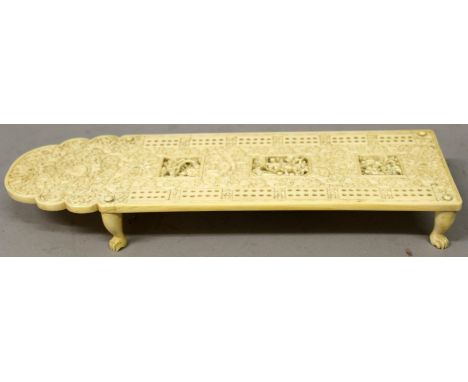 A FINE QUALITY 19TH CENTURY CHINESE CANTON IVORY CRIBBAGE BOARD,supported on four claw feet, the top surface carved in detail