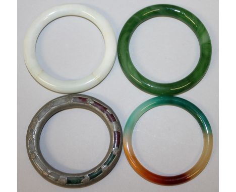 A GROUP OF FOUR CHINESE JADE-LIKE BANGLES, one overlaid with pewter, the largest 3.25in diameter. (4)