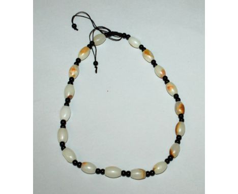 A CHINESE PALE CELADON JADE-LIKE NECKLACE, the oval beads with russet inclusions, approx. 18in long.
