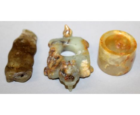 A CHINESE JADE ARCHER'S RING, the stone with russet and white inclusions, 1.25in diameter & 1.1in high; together with two oth